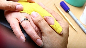 Eine Hand mit gelben Stoff liegt in einer anderen